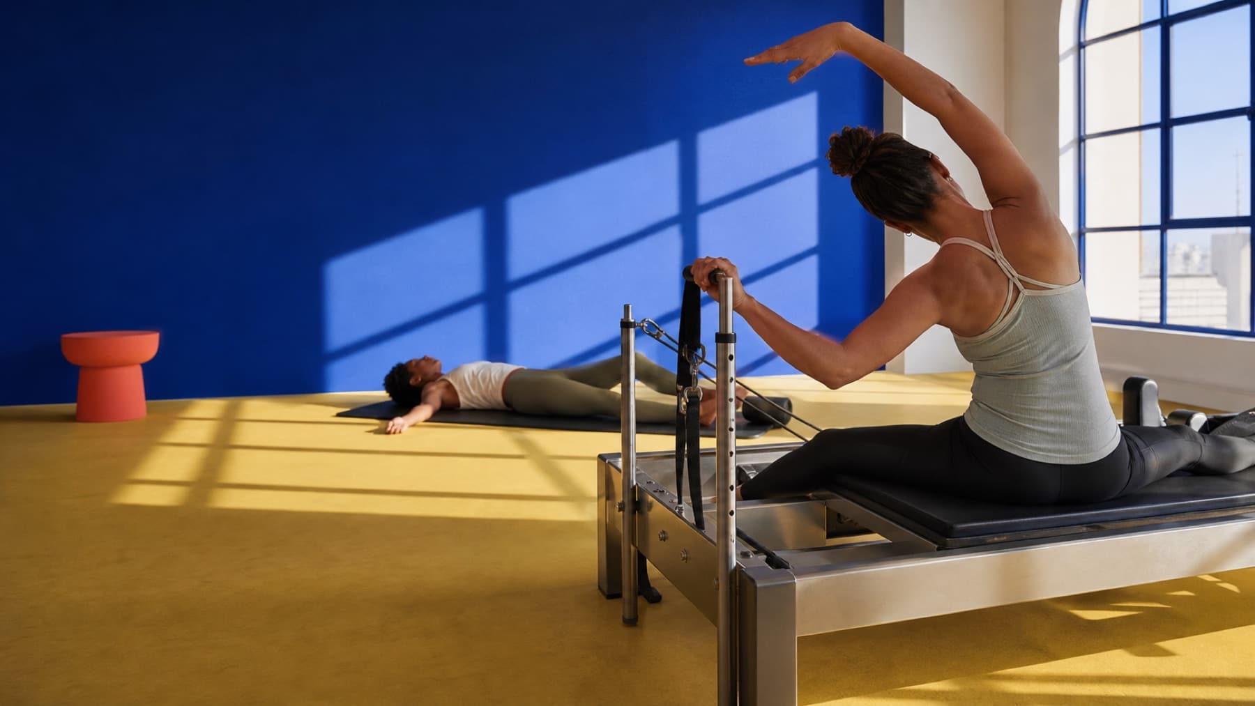 Deux personnes pratiquent le Pilates et le yoga dans un studio lumineux aux murs bleu cobalt